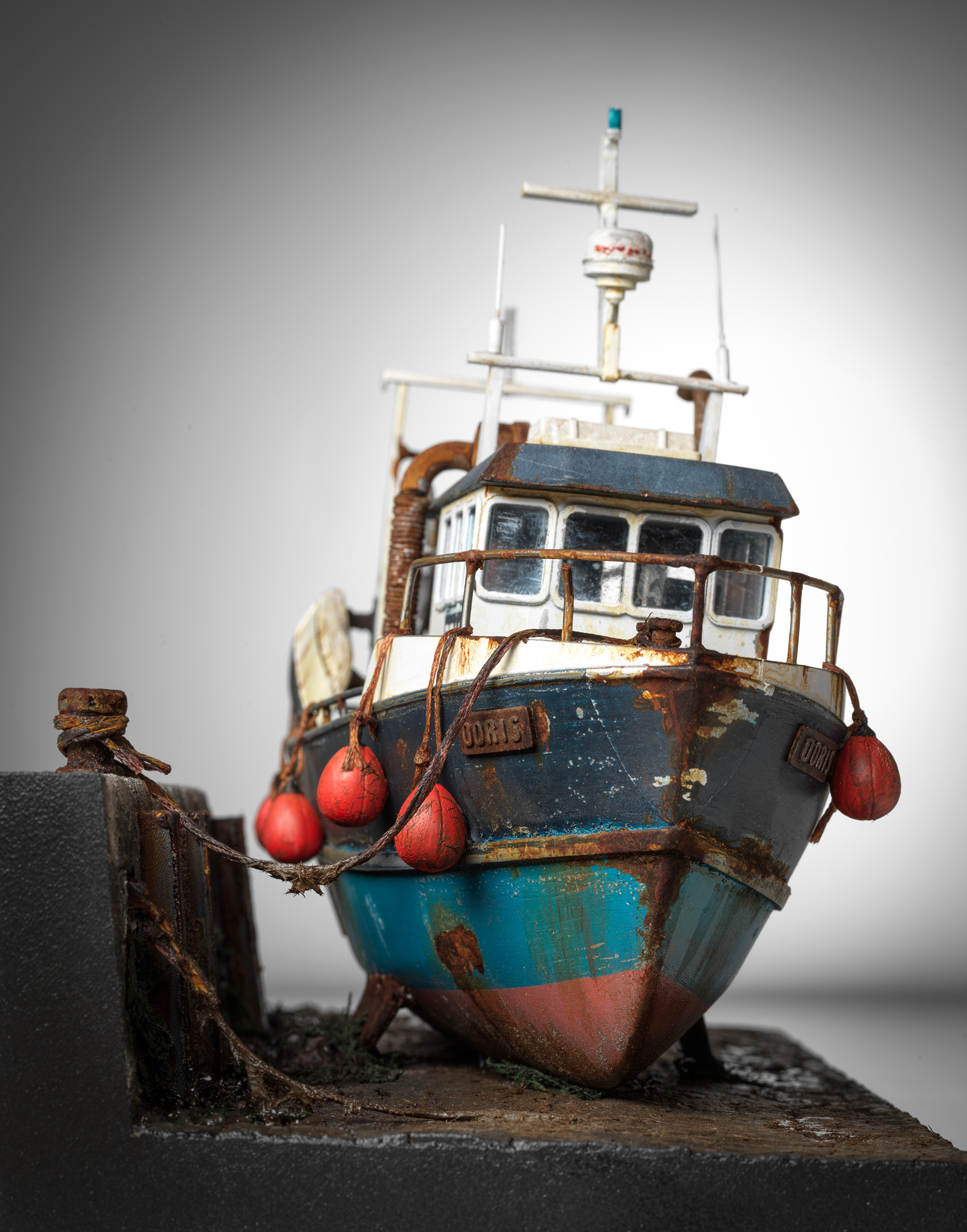 Doris seen bow-on beside the harbour wall, with red fenders and her mooring rope
