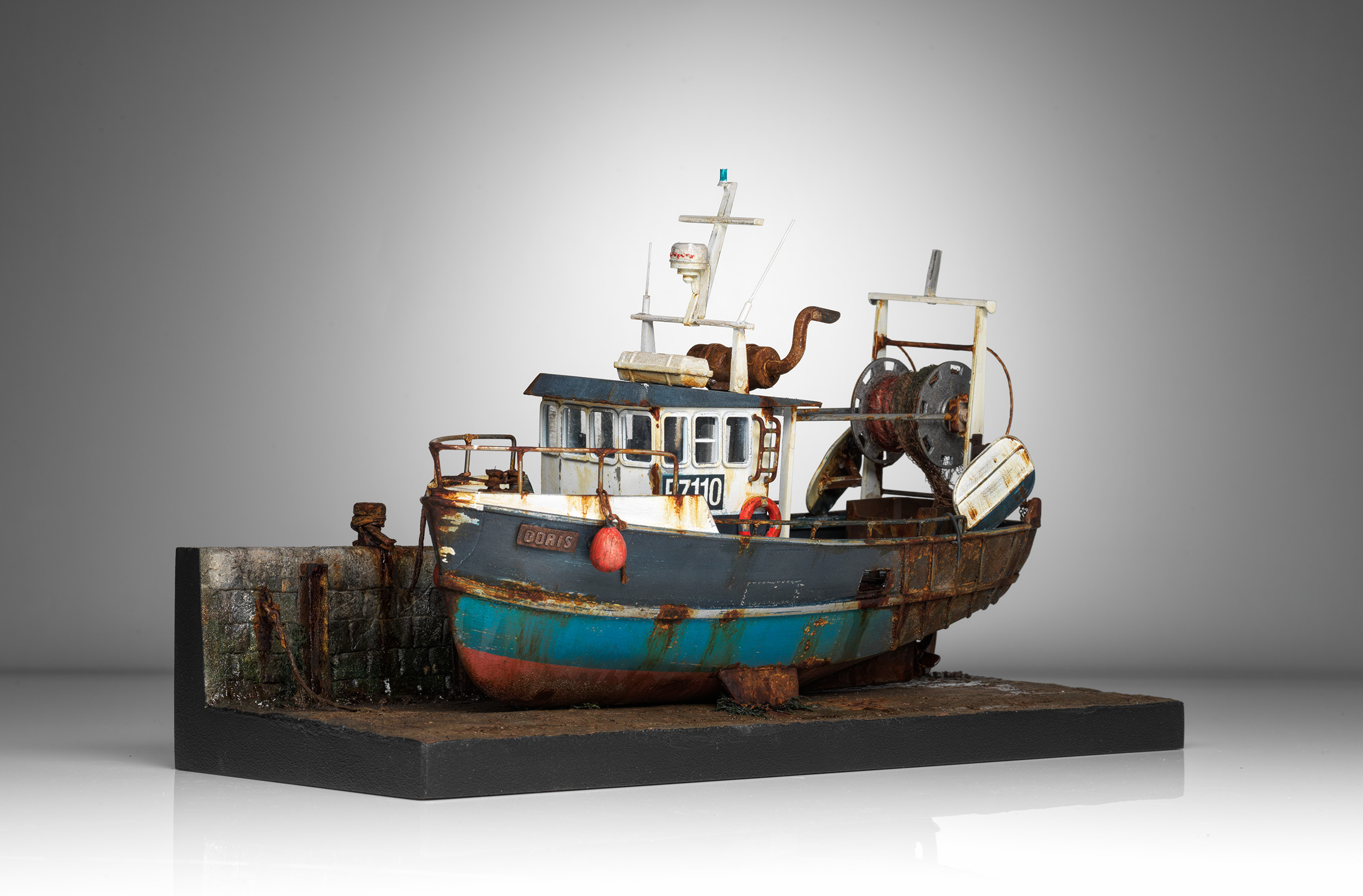 Complete front three-quarter view of Doris, with the harbour wall, red fenders and net gear