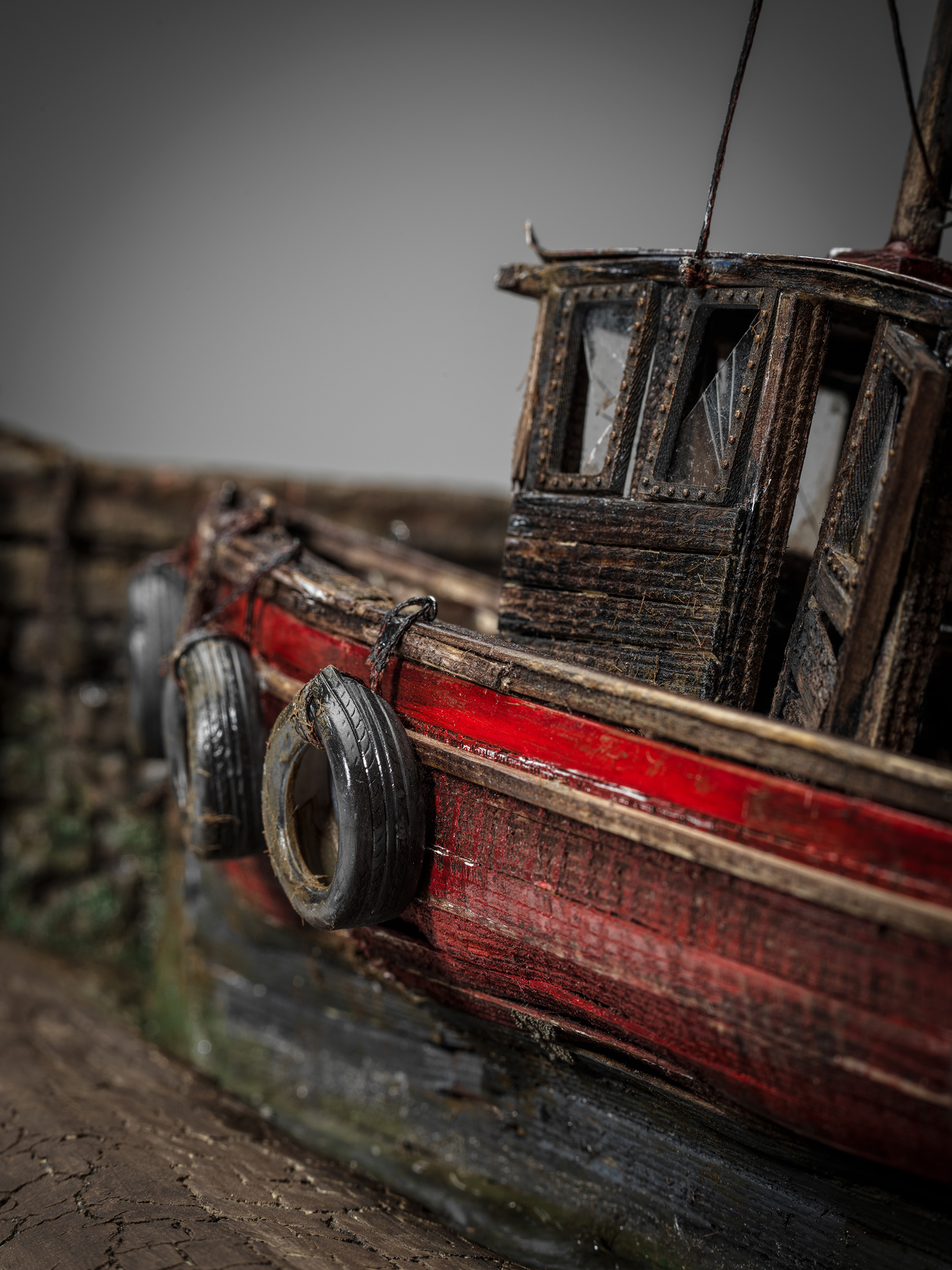 Close view along Mollie's weathered red hull and tyre fenders